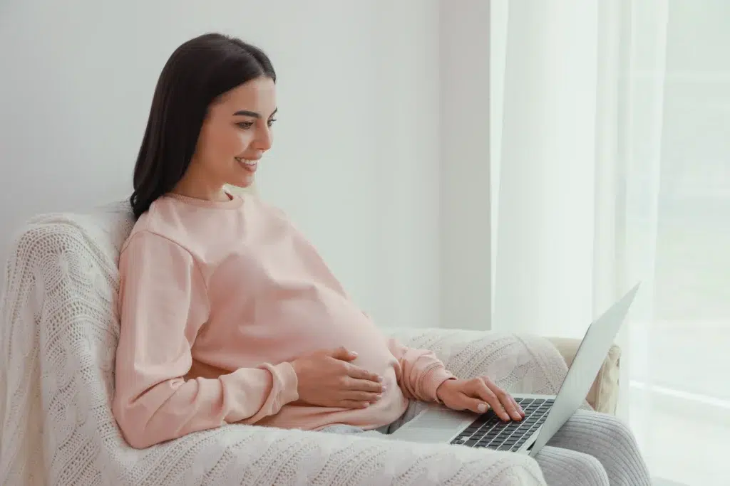 Pregnant woman on a couch using a laptop to learn about maternity care services and CPT 59400 billing changes