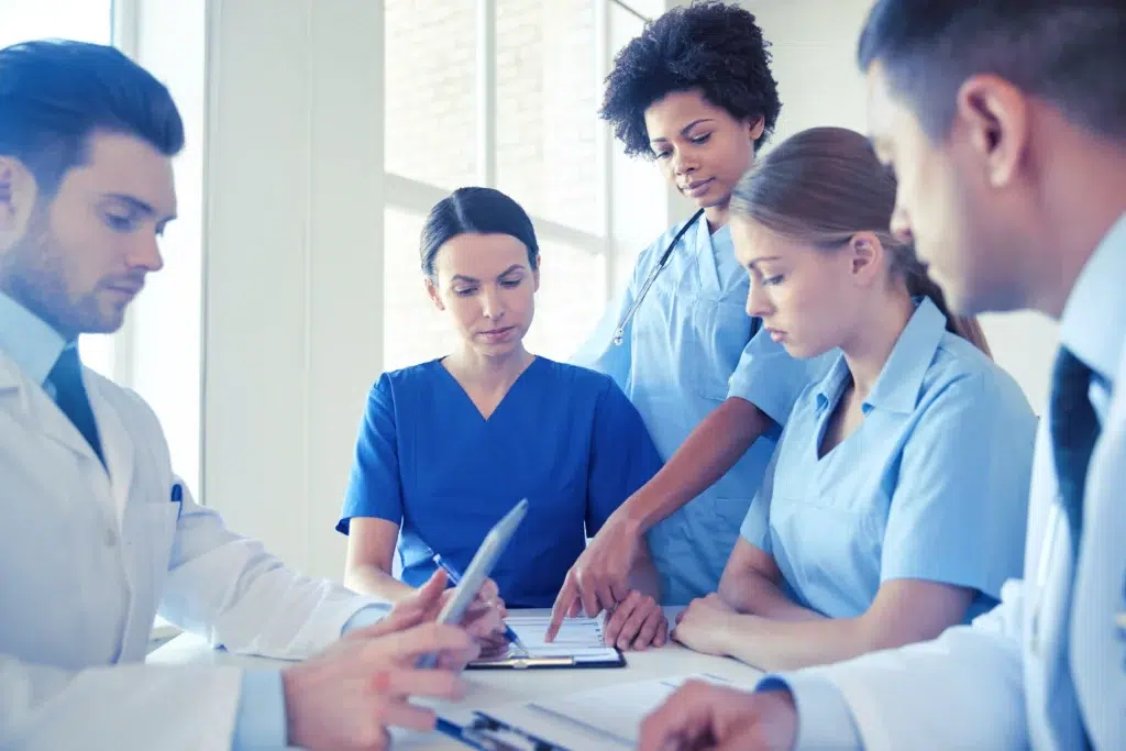 Group of clinicians meeting at a hospital office, representing the coordinated roles behind revenue cycle management staffing