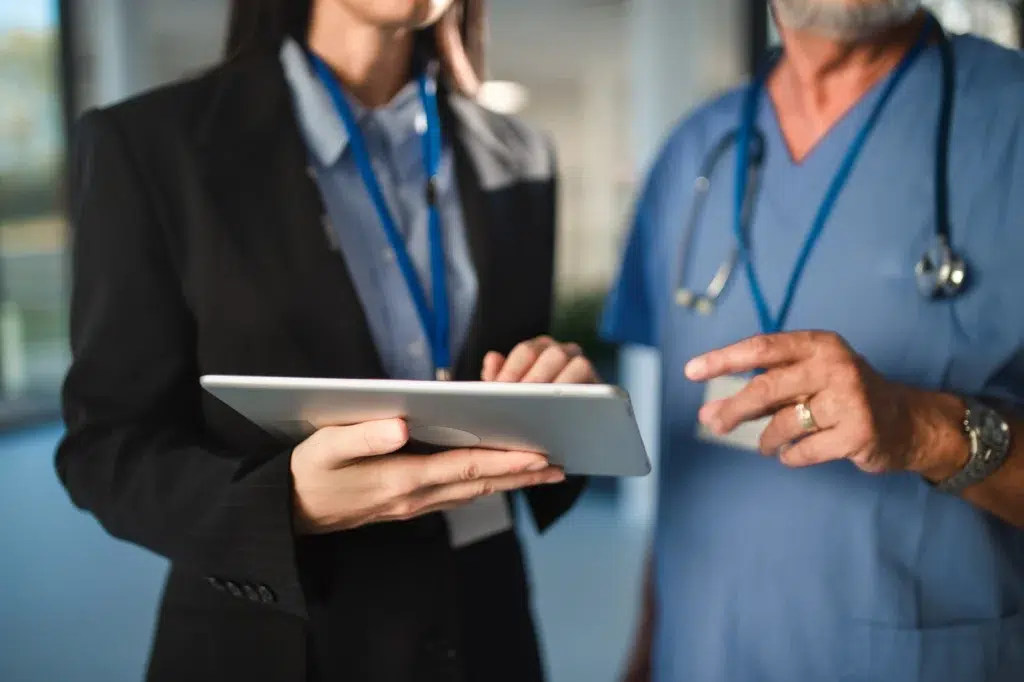 Two healthcare professionals reviewing data on a tablet, reflecting revenue cycle management staffing roles like accounts receivable management and physician credentialing services