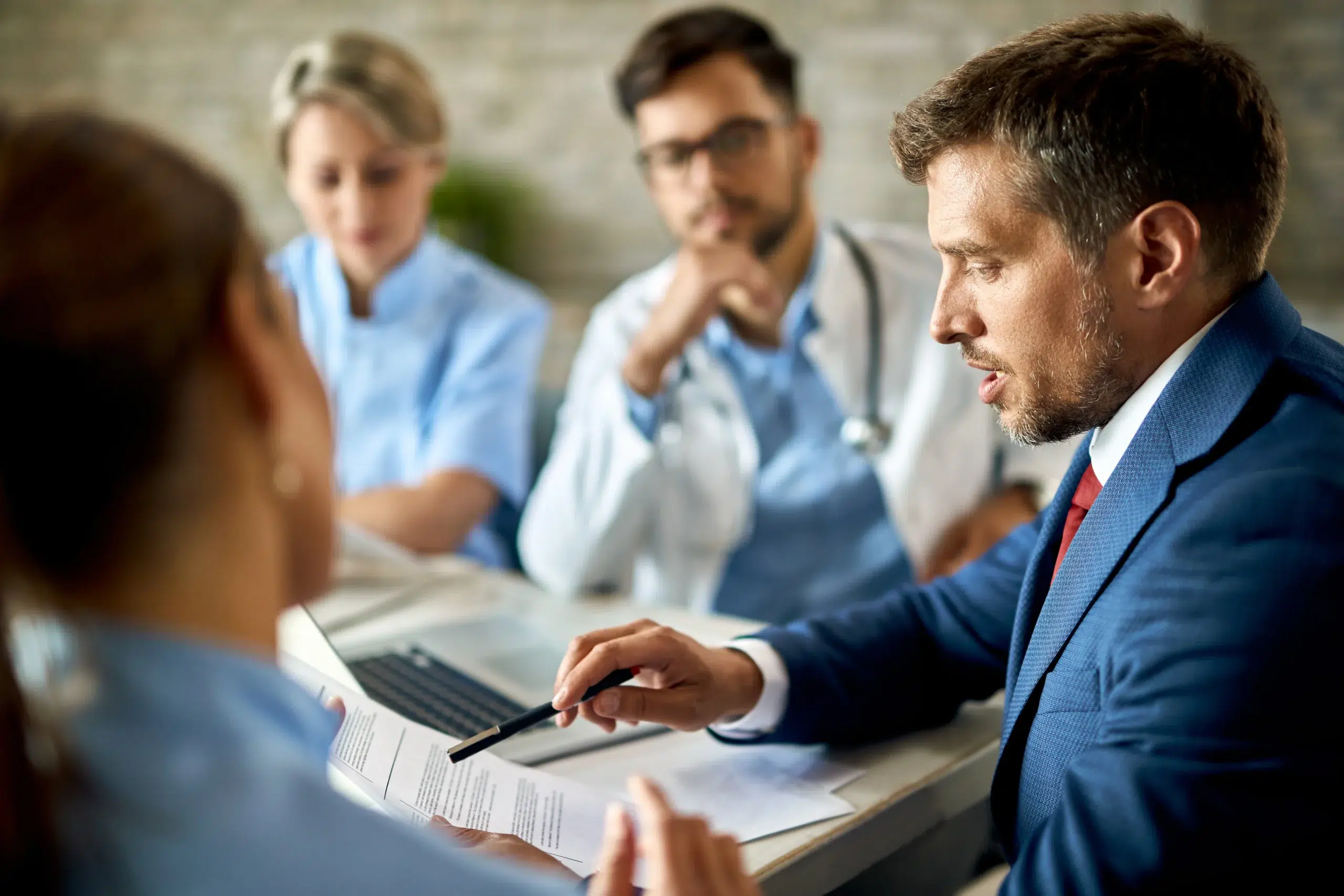 Medical team and an administrator discussing a patient case, the coordination required to negotiate and bill a single case agreement correctly