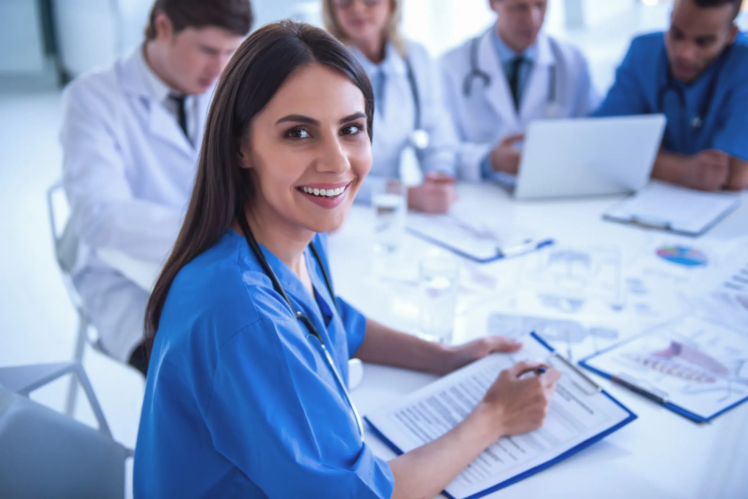 Healthcare professionals collaborating around a table with documents, the verification work behind medical credentialing services