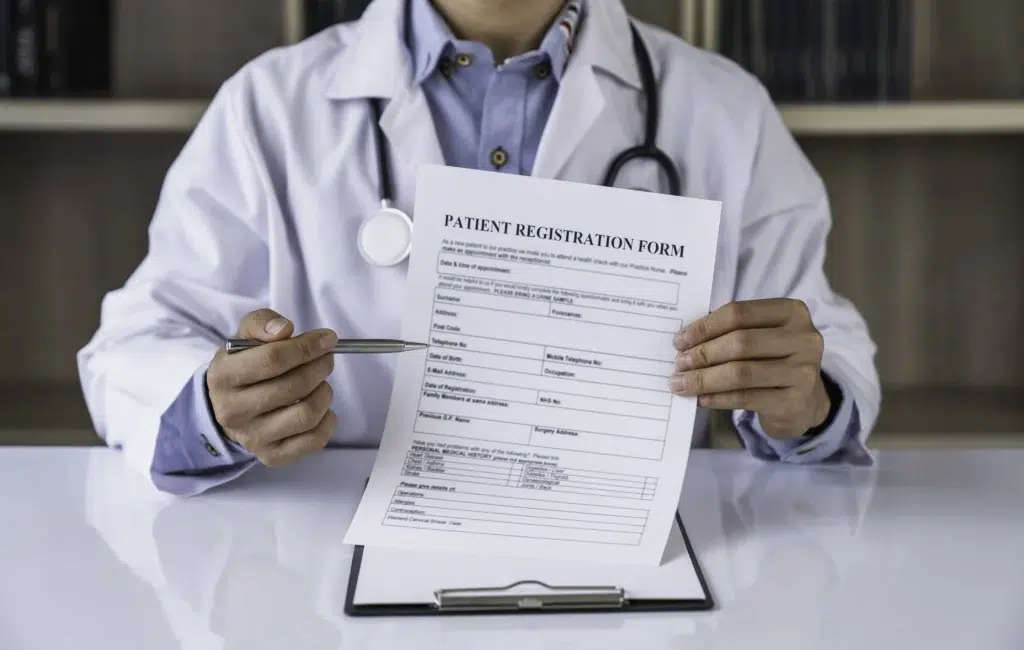 Physician reviewing a patient registration form, part of verifying drug and coverage details before billing CPT 96372