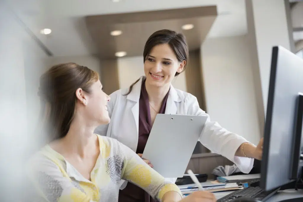 Physician reviewing coverage details with a patient at a computer, the verification step that identifies when a single case agreement is need