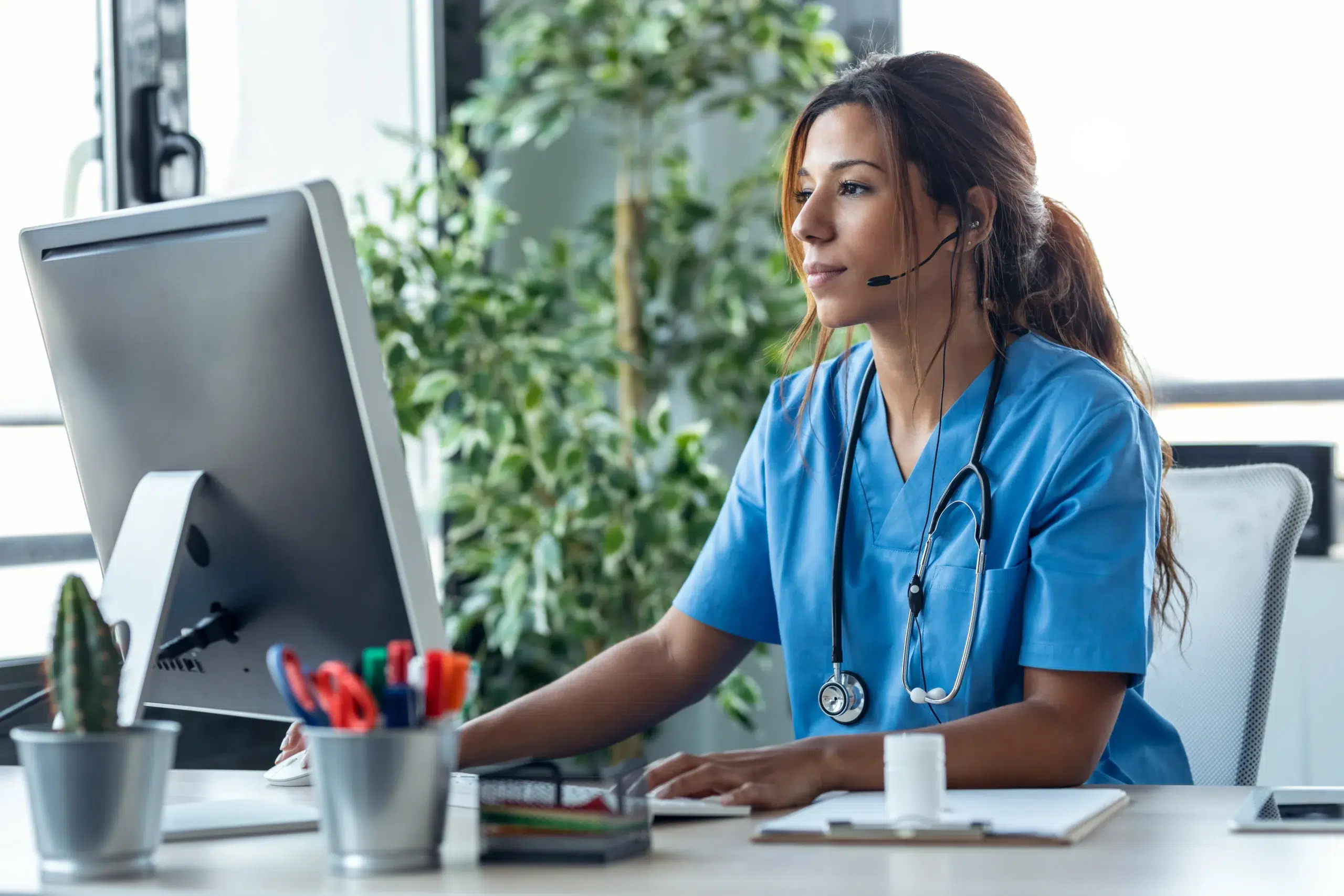 Medical biller working at a computer, verifying the diagnosis and procedure codes on a superbill to prevent claim denials